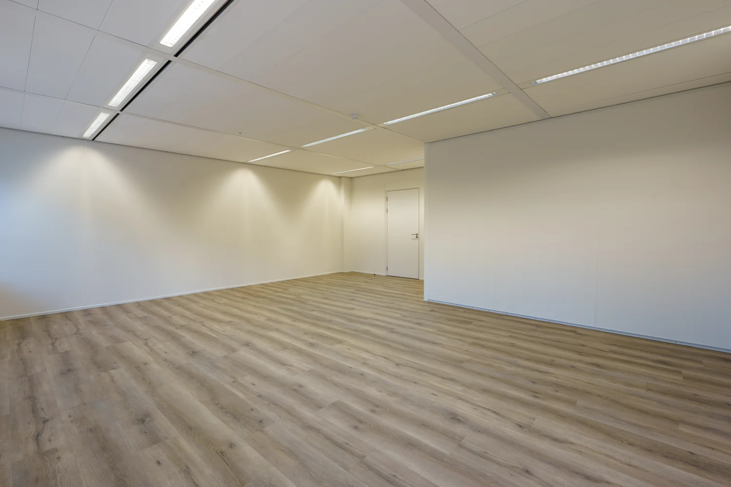Leeg kantoor met houten vloer, witte muren en systeemplafond aan de Baarnsche Dijk.